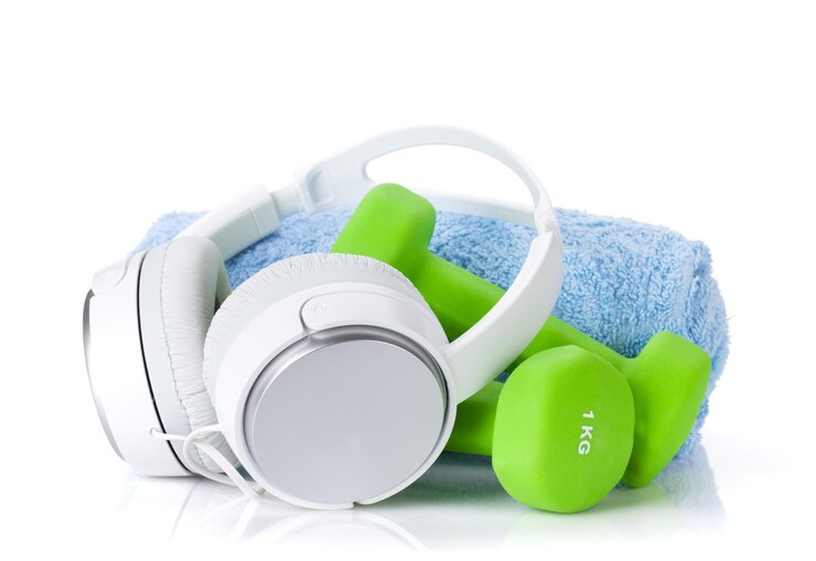 White headphones with green dumbbells and a blue towel on a white background